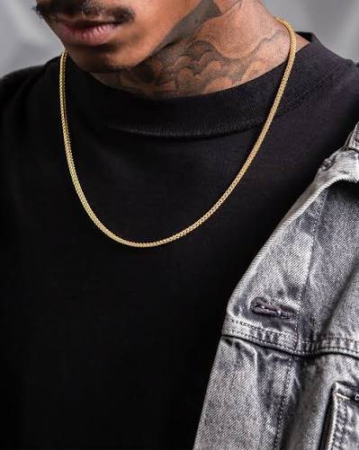 Man wearing a thin gold Franco chain over a black shirt, showing the dense smooth links